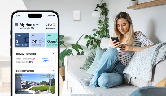 Woman using a smartphone app on a smart home device in a living room. A smartphone app screen displays a live feed of a front porch and indoor temperature.
