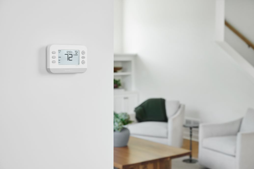 X2S thermostat installed on wall with living room in background